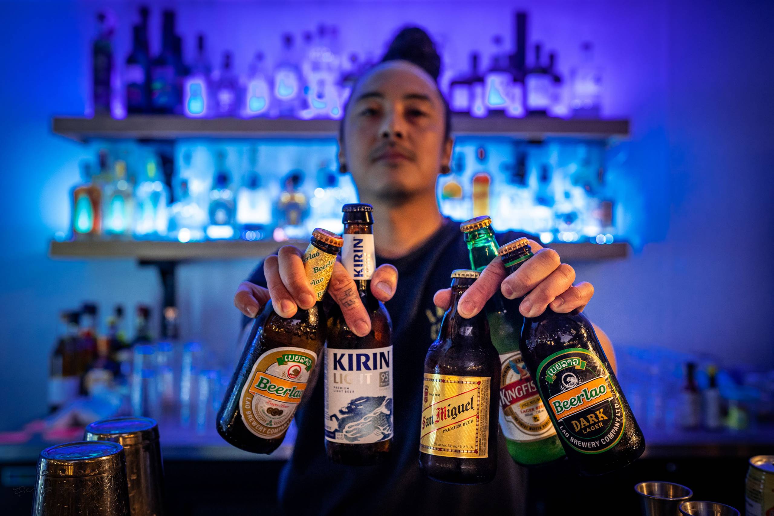 A bartender shows off an array of international beers, including Beerlao, Kingfisher and San Miguel.