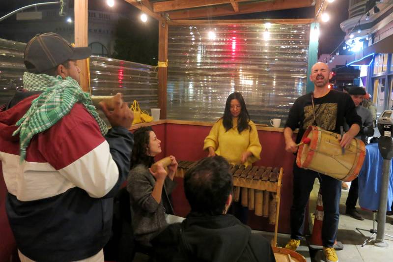 Federico Ardila and May-Li Khoe play percussion instruments in a restaurant parklet in San Francisco.