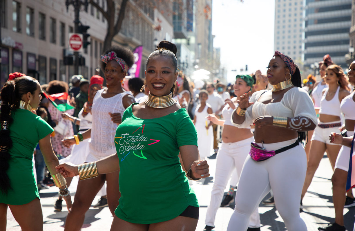 A dance group in green and white smiles 
