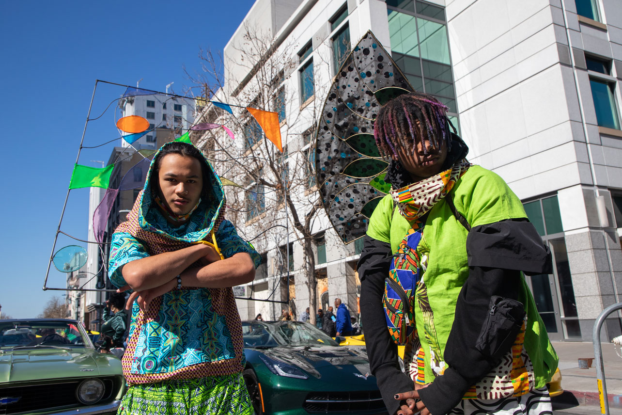 Two young people wear brightly colored, futuristic outfits