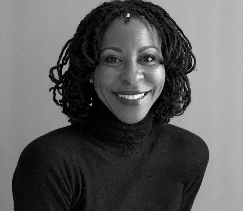 A Black woman in a black turtleneck in a black-and-white headshot pose.