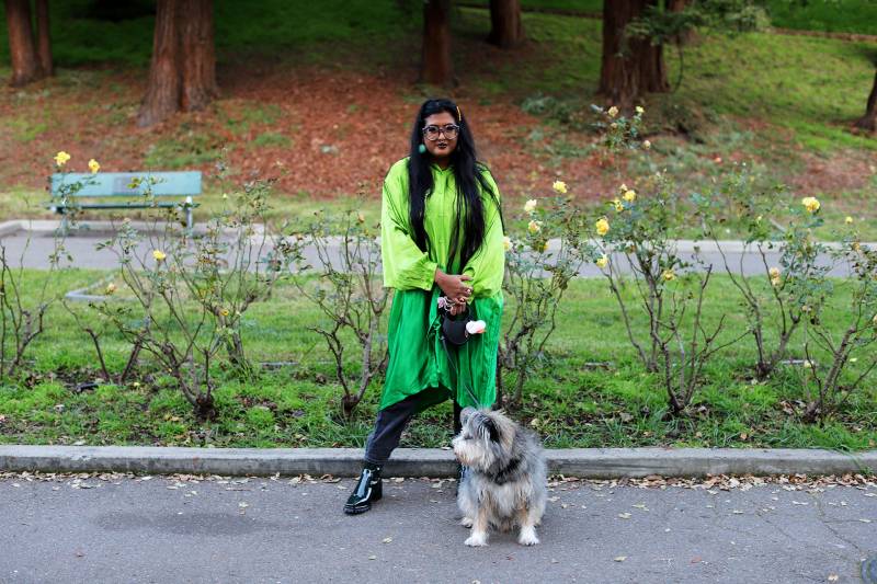 A portrait of electronic musician Sharmi Basu with their dog Beni at the Oakland rose garden.