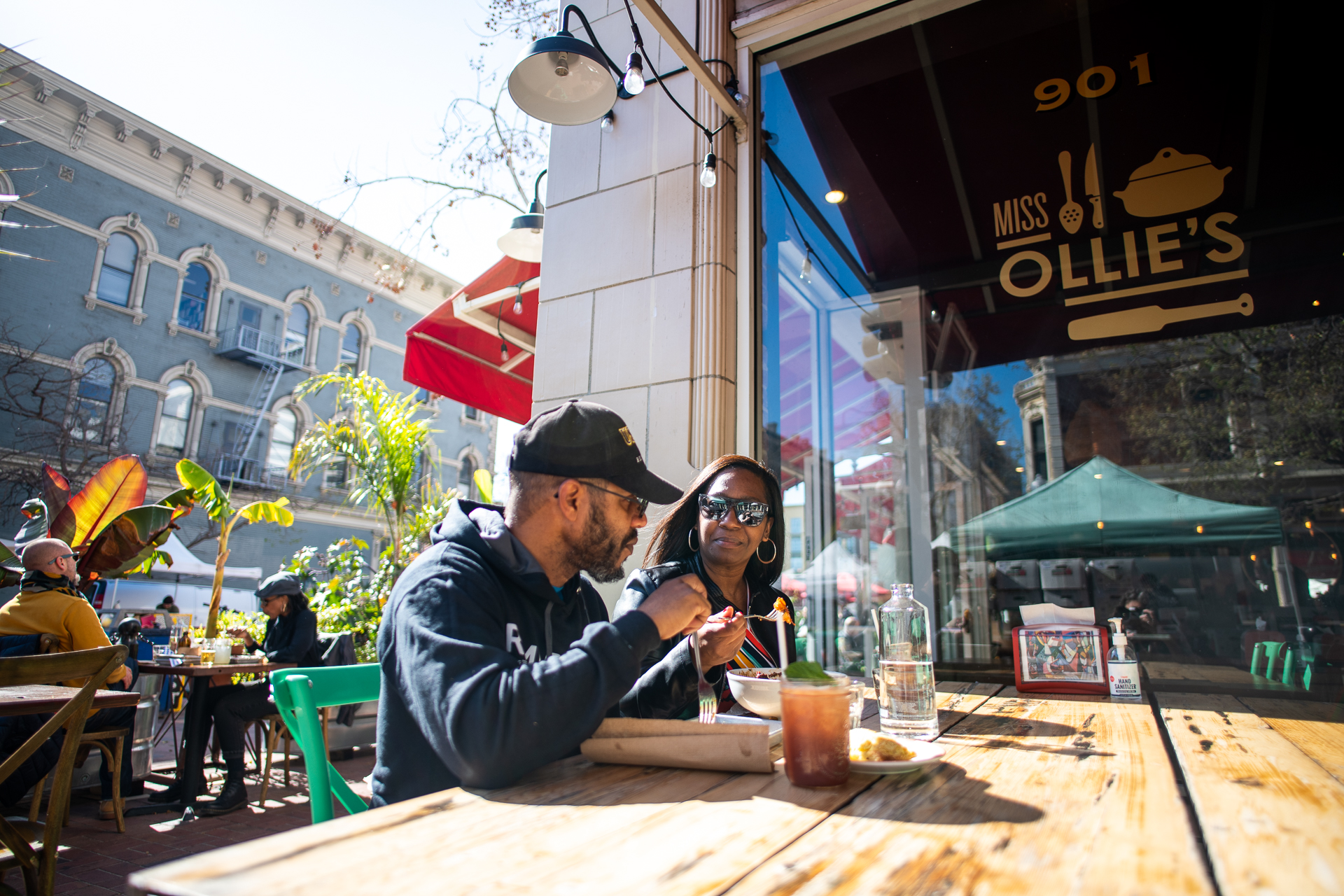 Two customers sit at a wooden table outside of Miss Ollie's in Old Oakland.