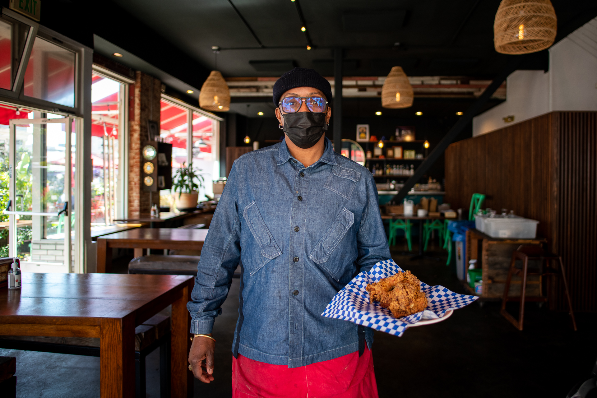 Wearing a face mask, chef Sarah Kirnon holds a plate of fried chicken at Miss Ollie's, her Old Oakland restaurant.