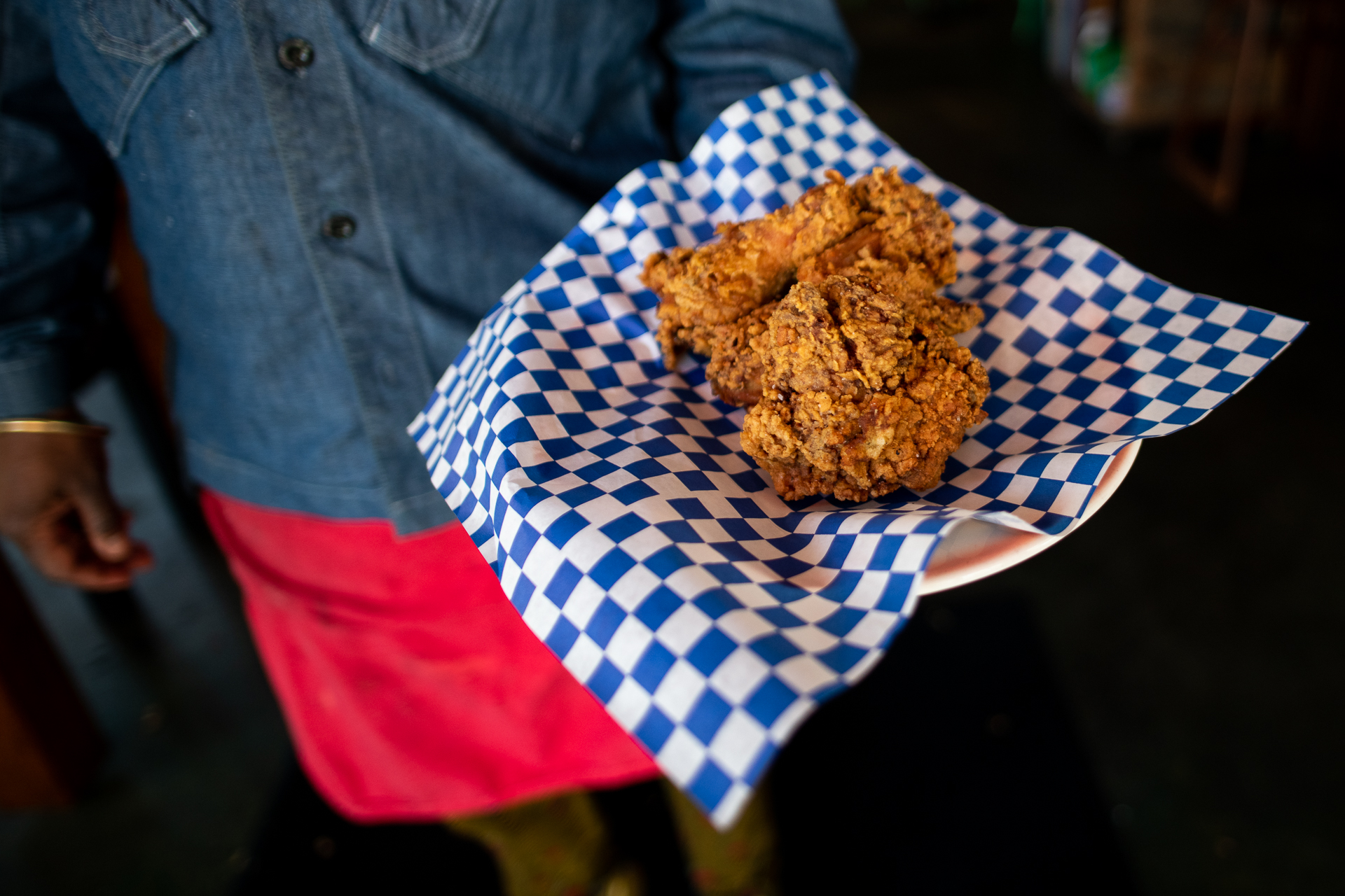 A piece of fried chicken on blue-and-white checkered paper.