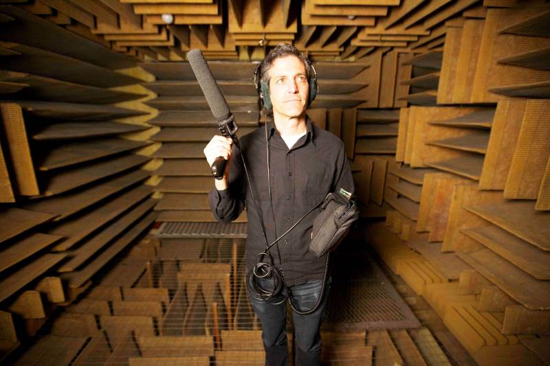 A man stands with a microphone in a soundproof room 