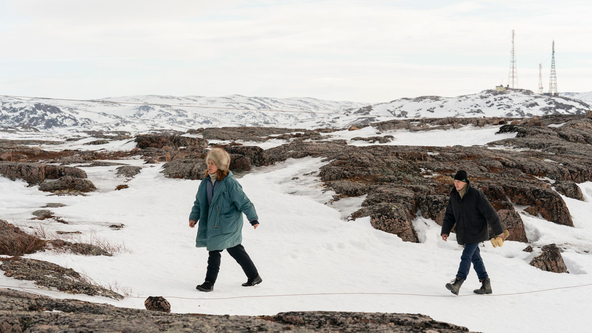 Woman and man in winter coats and had in snowy uninhabitated landscape