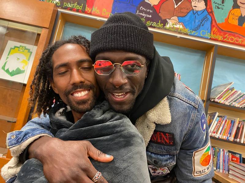 School administrator Moses Omolade and educator Maurice Andre San-chez share an embrace inside of Westlake Middle school's library on February 18, 2022-- the day the OUSD school board voted on the planned closure of a number of schools.