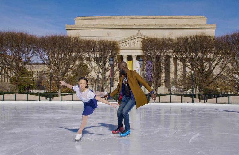 A teenage ice skater Zuri Jones is skating with her coach at an outdoor rink.