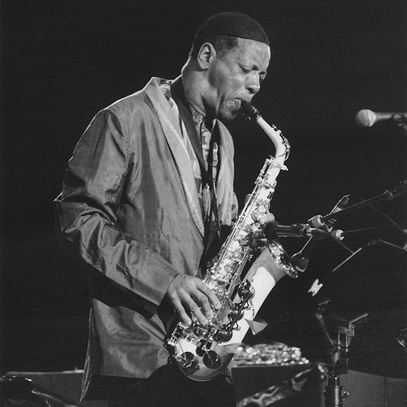 A man plays a saxophone, slightly hunched over