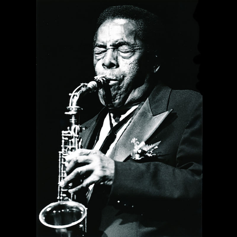 A man plays a saxophone, eyes closed