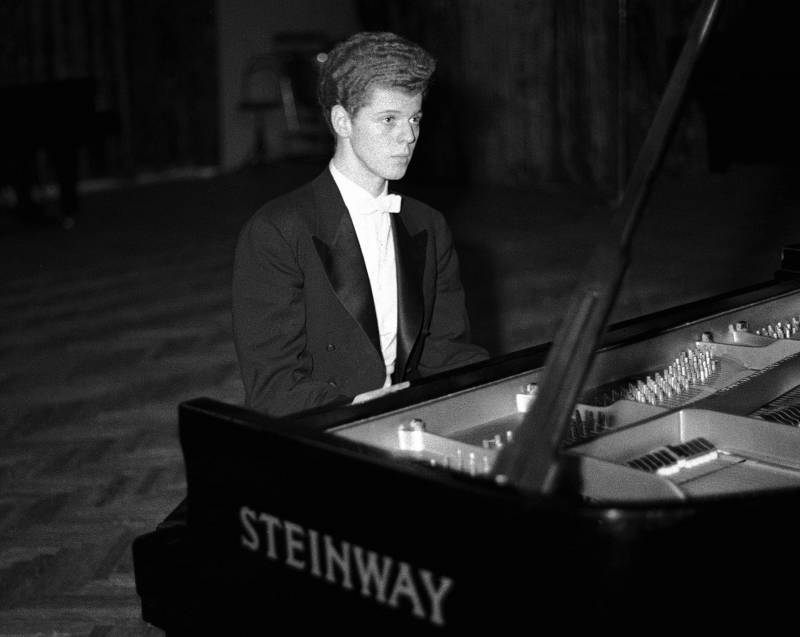 A young man, wearing a tuxedo, sits at a grand Steinway piano.