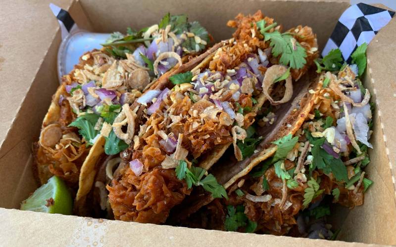 Three vegan quesabirria tacos in a takeout container.