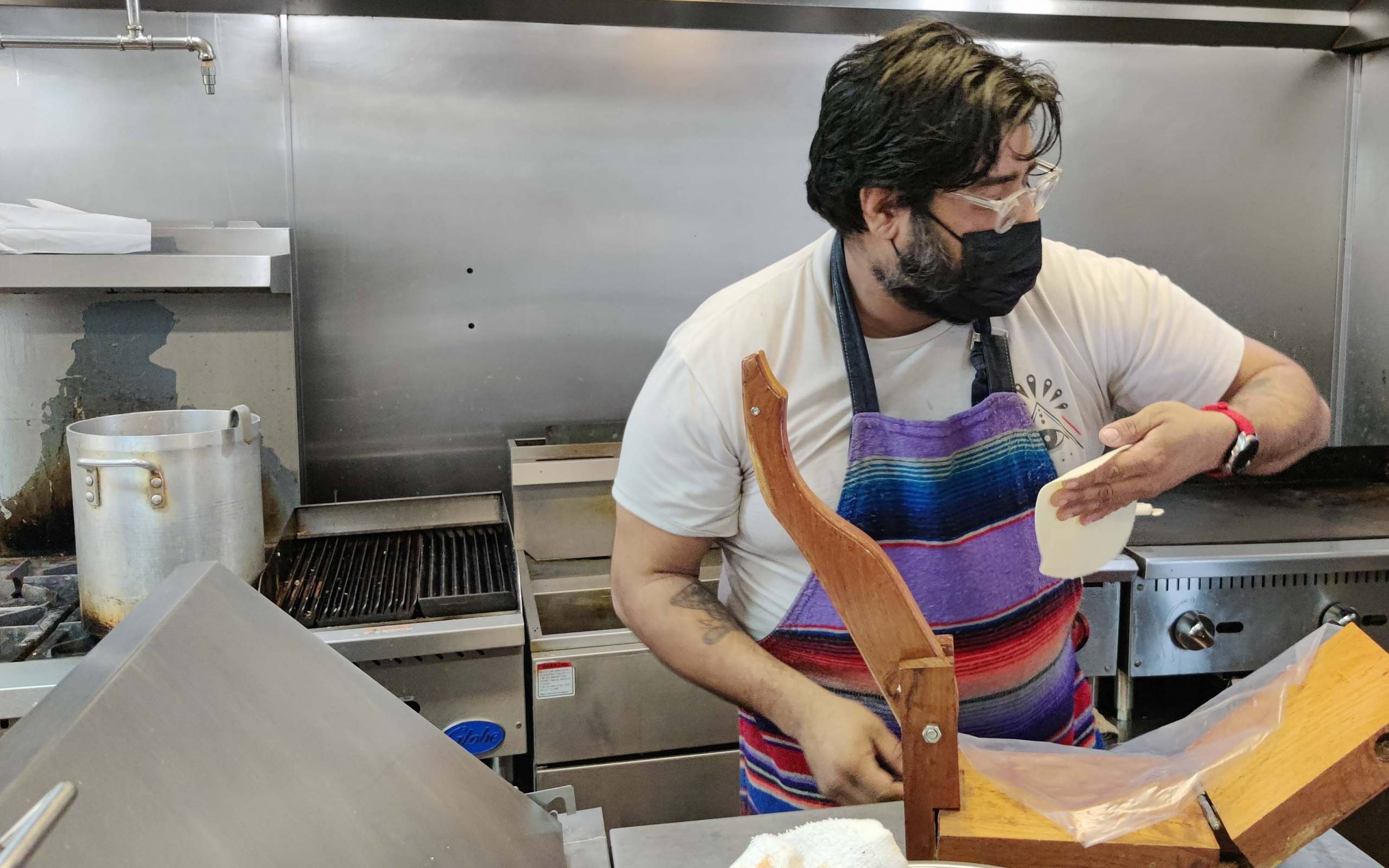 Chef Raul Medina presses a tortilla by hand.