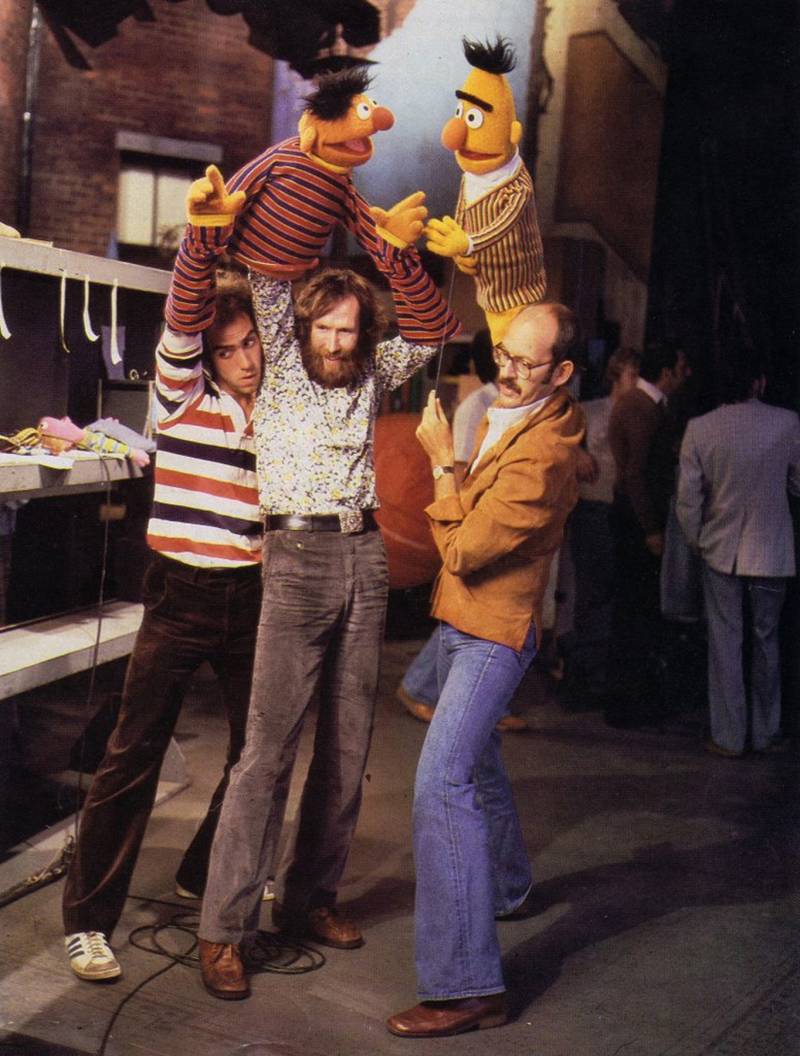 Three puppeteers hold up iconic Bert and Ernie puppets on the set of 'Sesame Street'