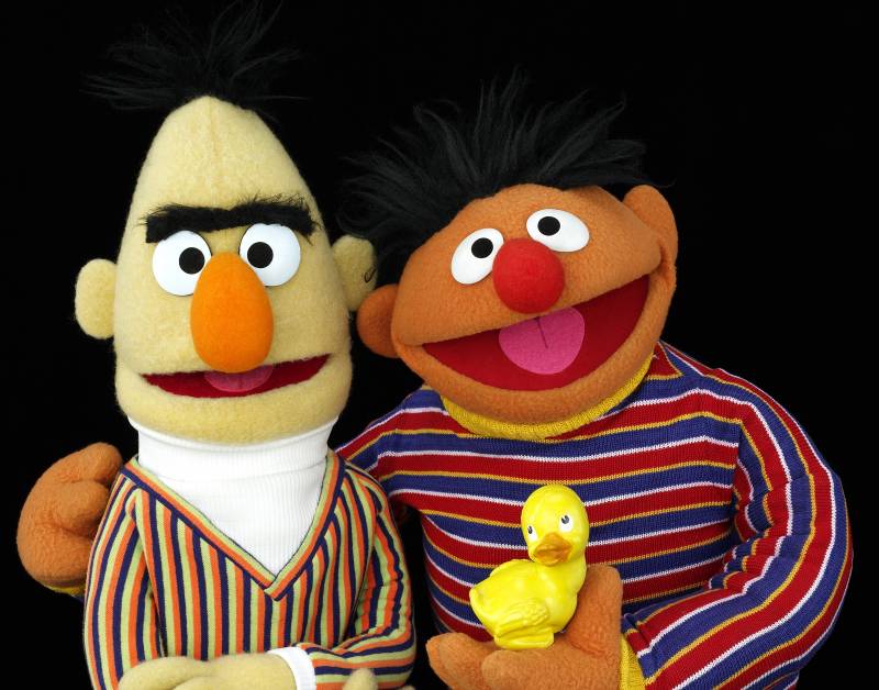 Two puppets in striped sweaters. One holds a rubber duck.