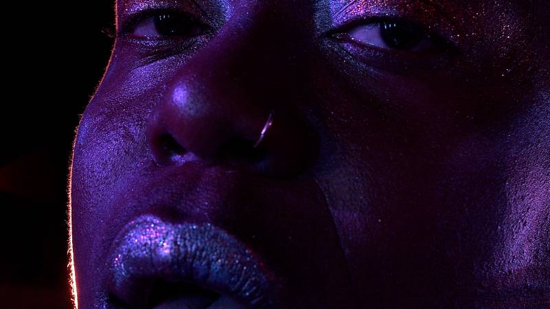 A close up of an African-American man's face in purple light.