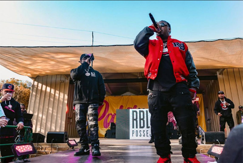 A rap group performs on an outside stage during the day