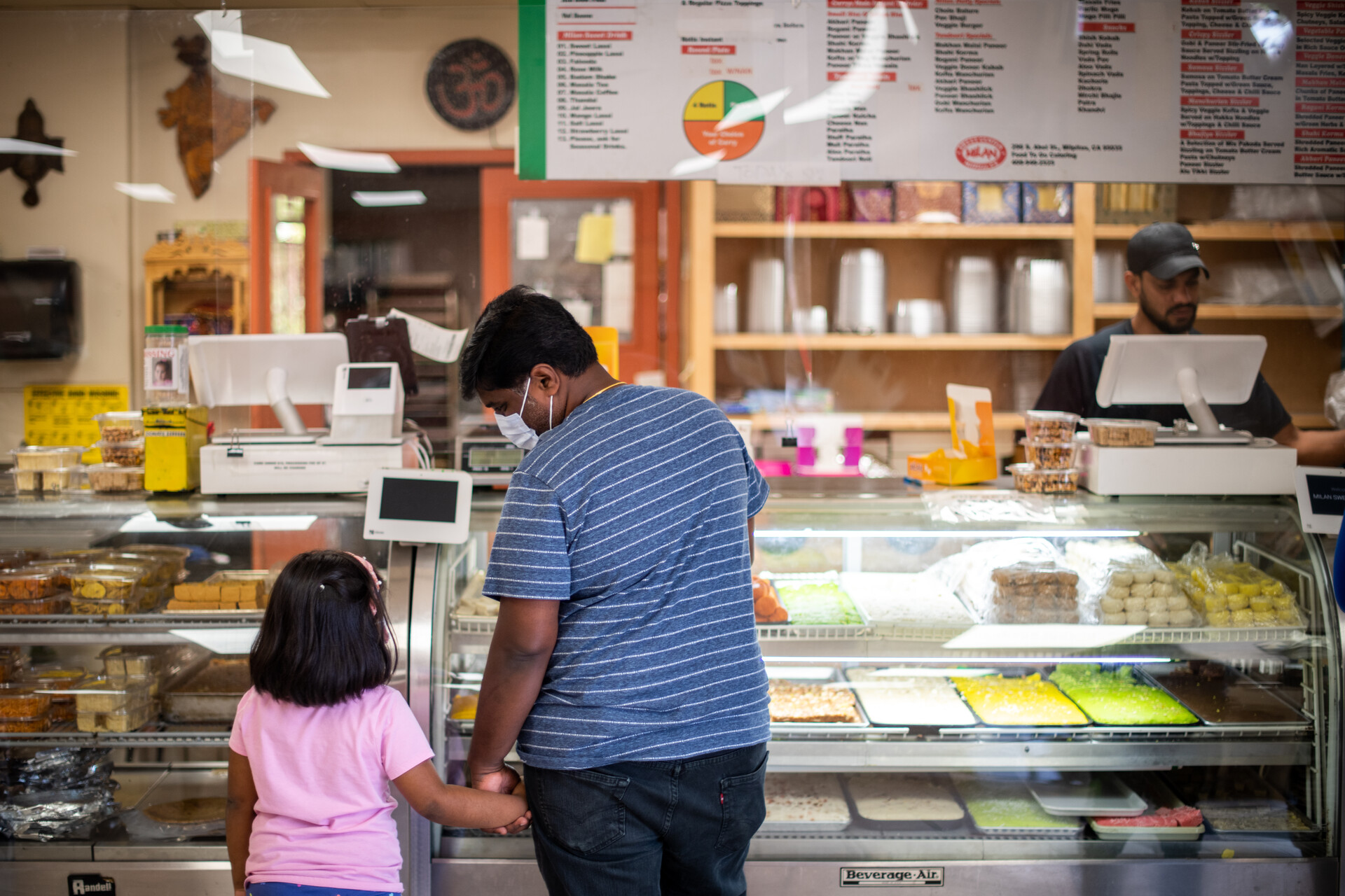 A father and daughter hold hands as they browse the display of sweets at Milan Sweet Center in Milpitas.