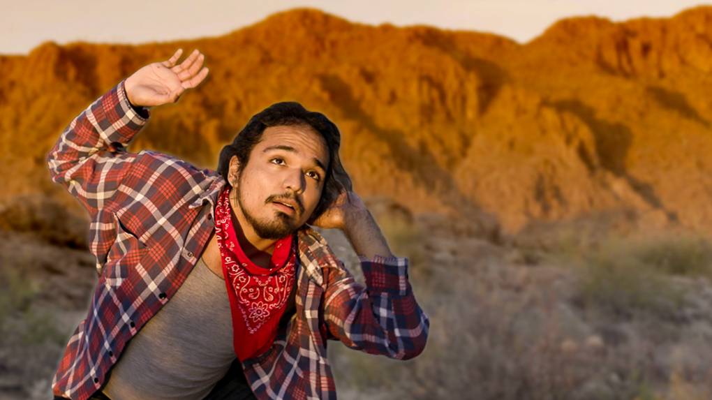 A male dancer stands mid-pose with the Arizona mountains behind him during golden hour