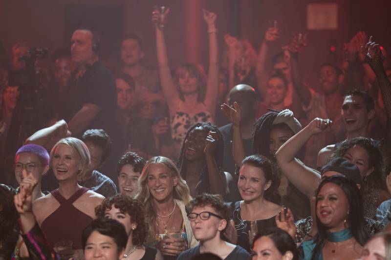 a crowded party scene with people cheering and raising their arms