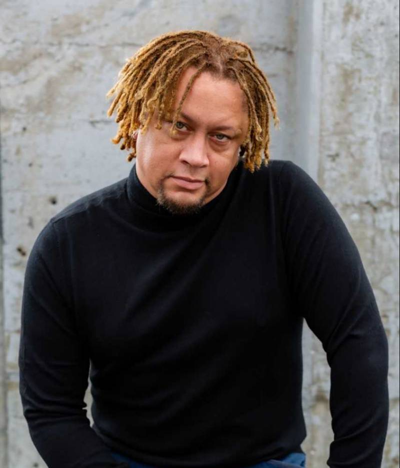 Poet Dazié Grego wears a black sweater while posing and looking directly into the camera.