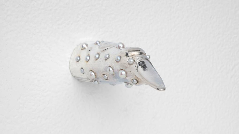 Shiny silver finger with pointed nail and pearls all over