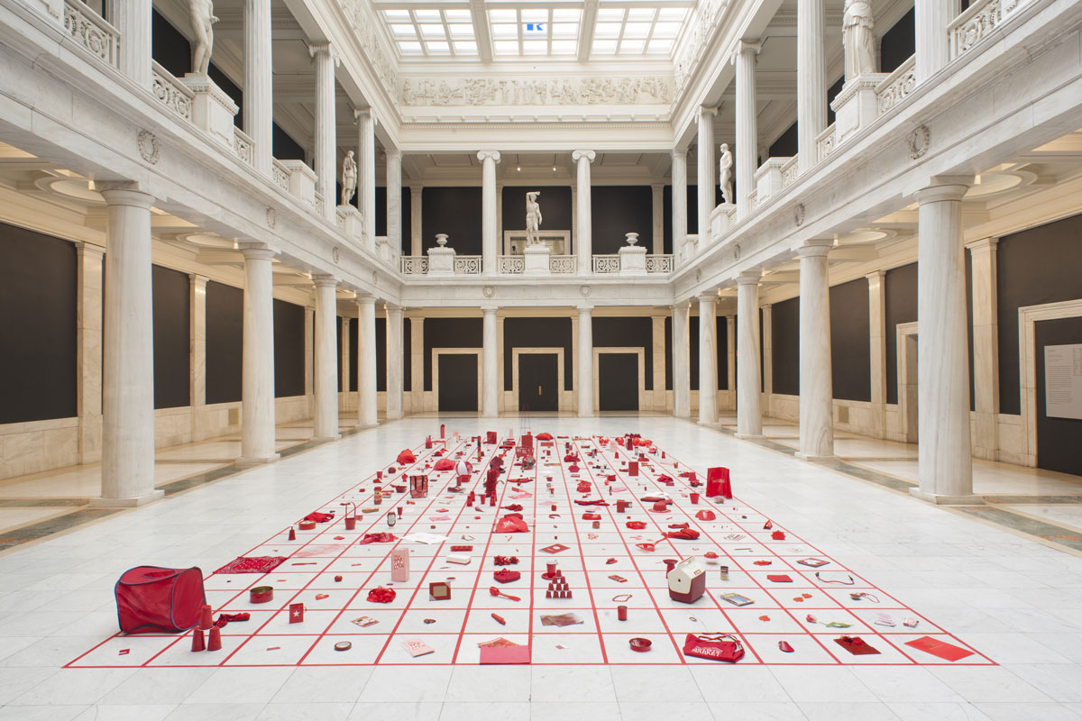 Ornate white stone atrium with grid of red objects on floor