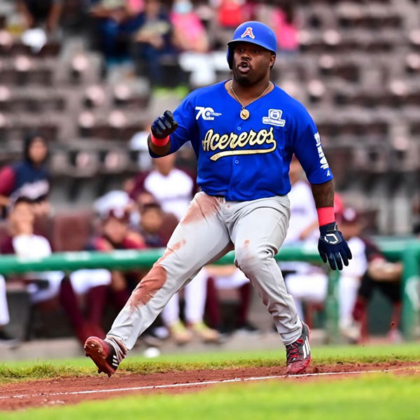 A man in a blue baseball uniform runs the bases on the baseball diamond.