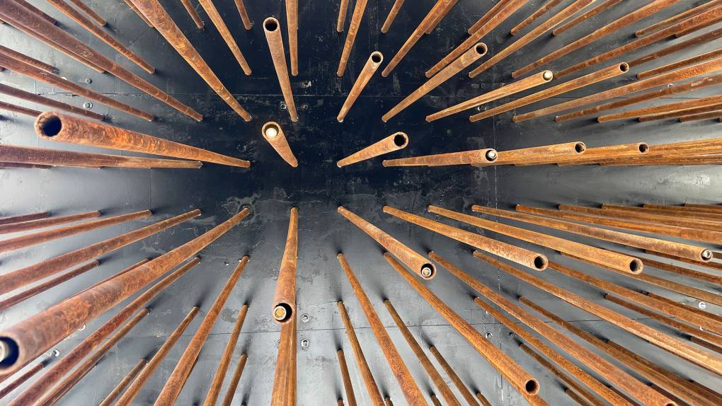The rusted steel pipes and electric lights that adorn the Society's Cage art installation.