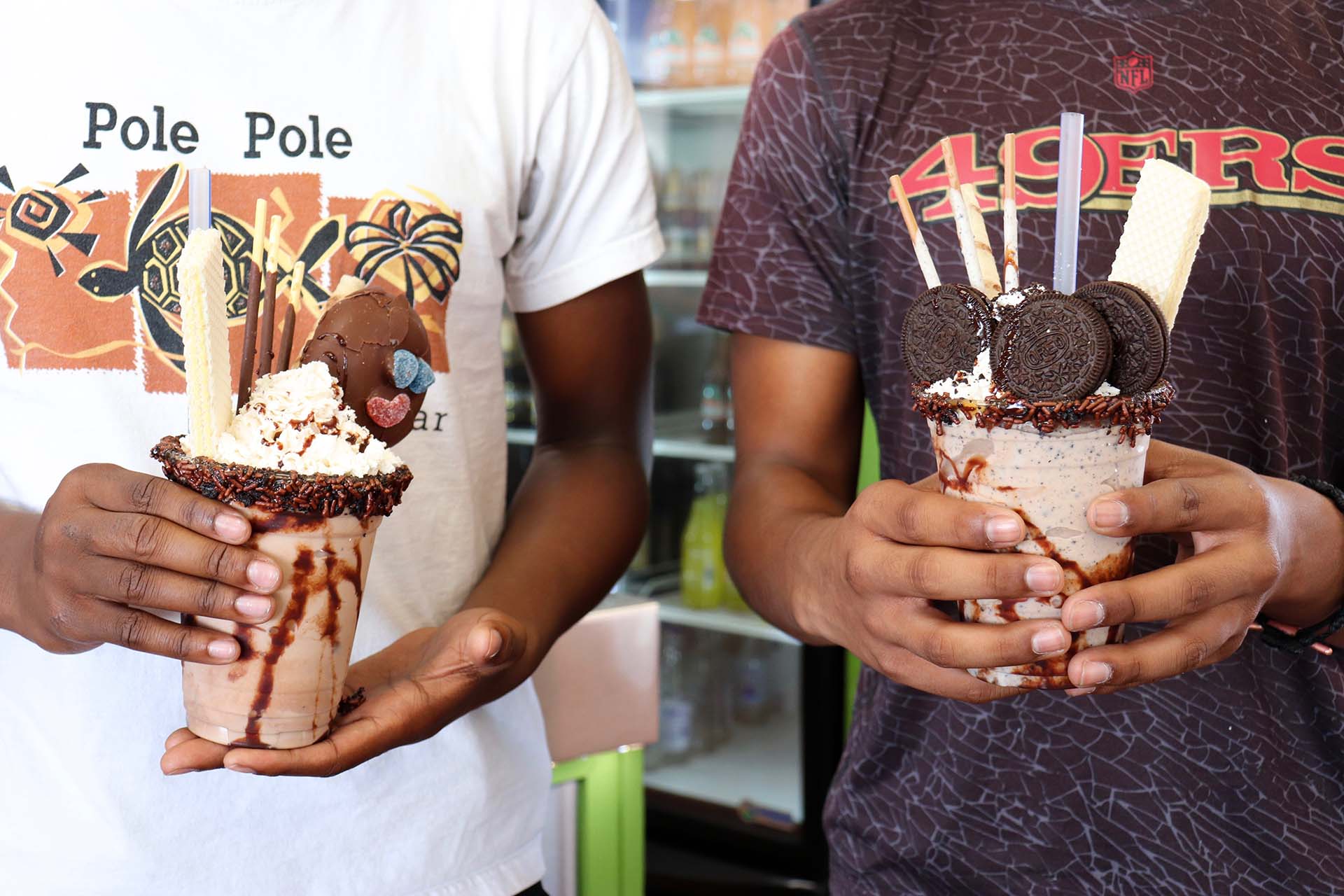 Two youngsters show off milkshakes loaded with sweet toppings.