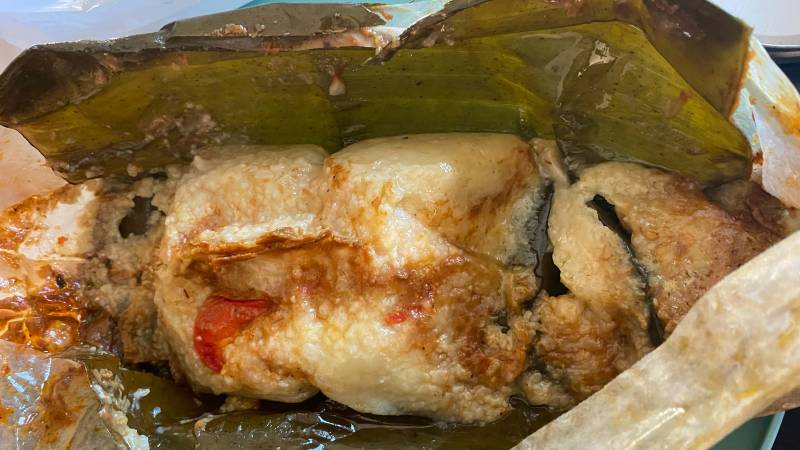 Closeup of a Guatemalan rice tamale, the banana leaf opened to expose its saucy interior.