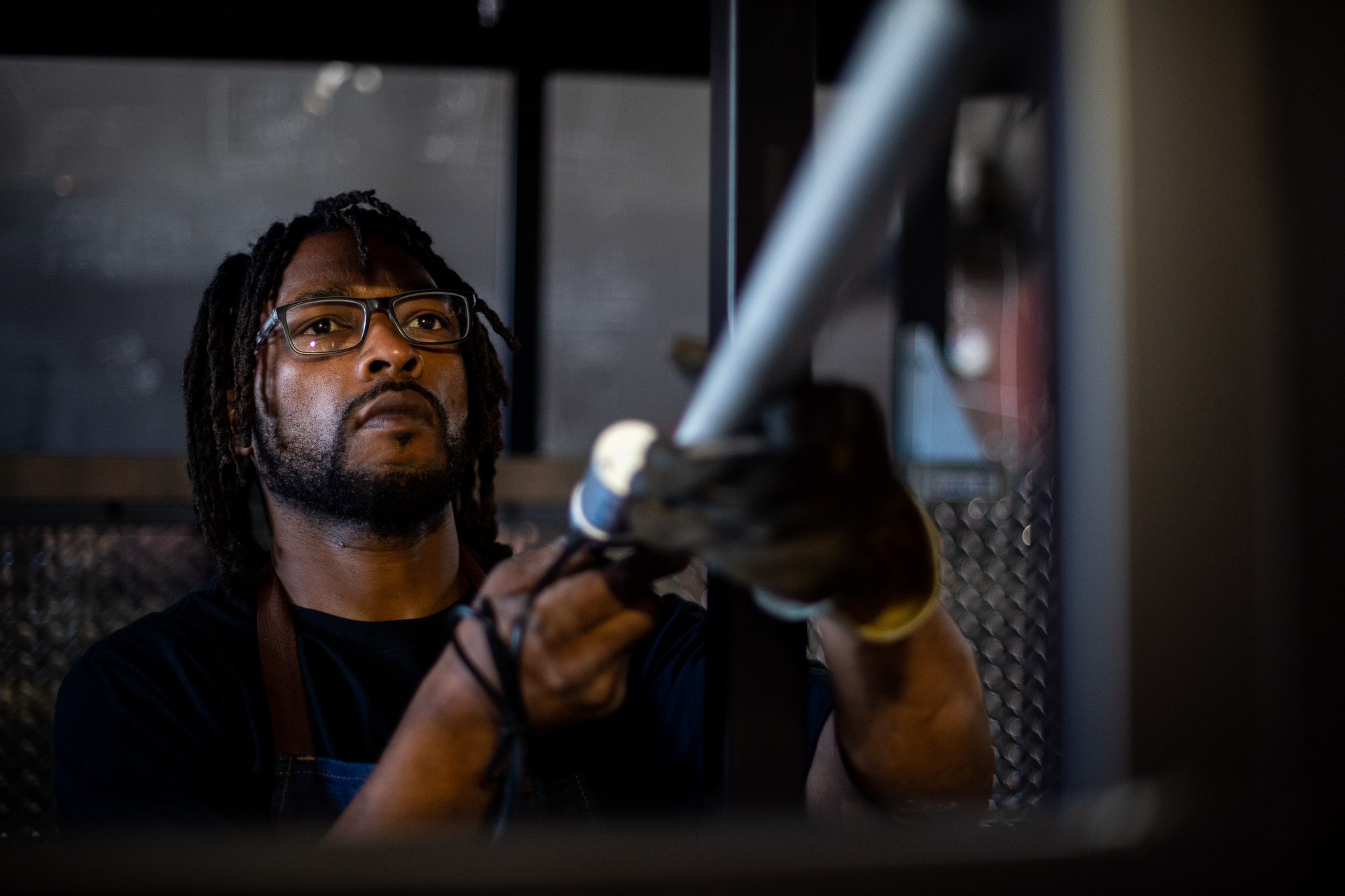 Man looks up pensively as he works with metal equipment.