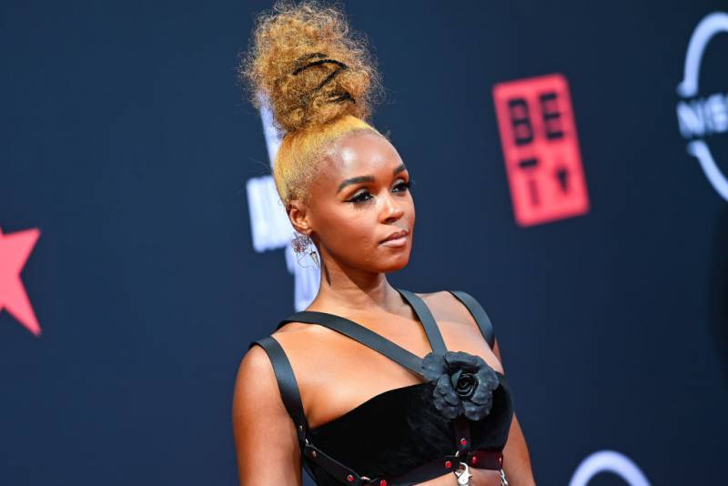 A Black woman in a black dress and styled hair poses on the red carpet