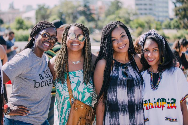 four young women pose and smile in a park during a Juneteenth celebration