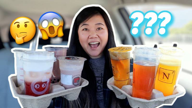 An Asian young woman holds a tray of boba drinks in each hand. Above her, there is a thinking face emoji and a scream emoji.