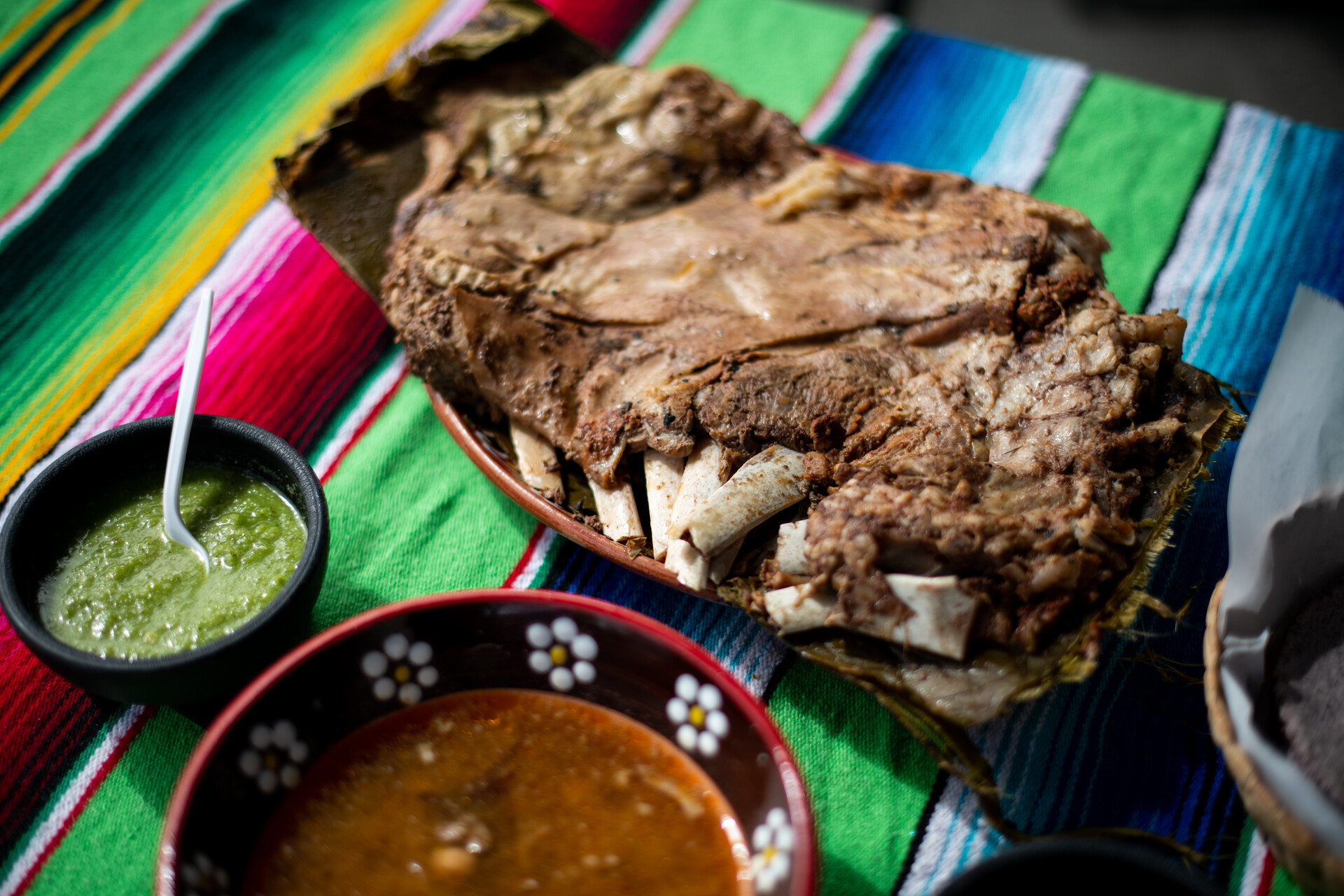 A plate of barbacoa on the bone, with a bowl of consomé on the side.