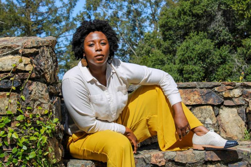 A Black woman with short hair sitting on outdoor stone steps