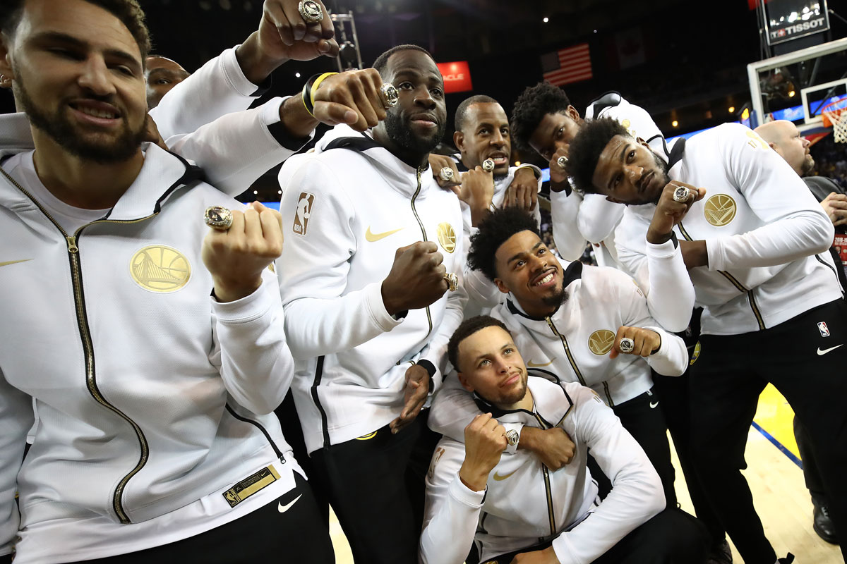 Basketball players in group photo holding up championship rings