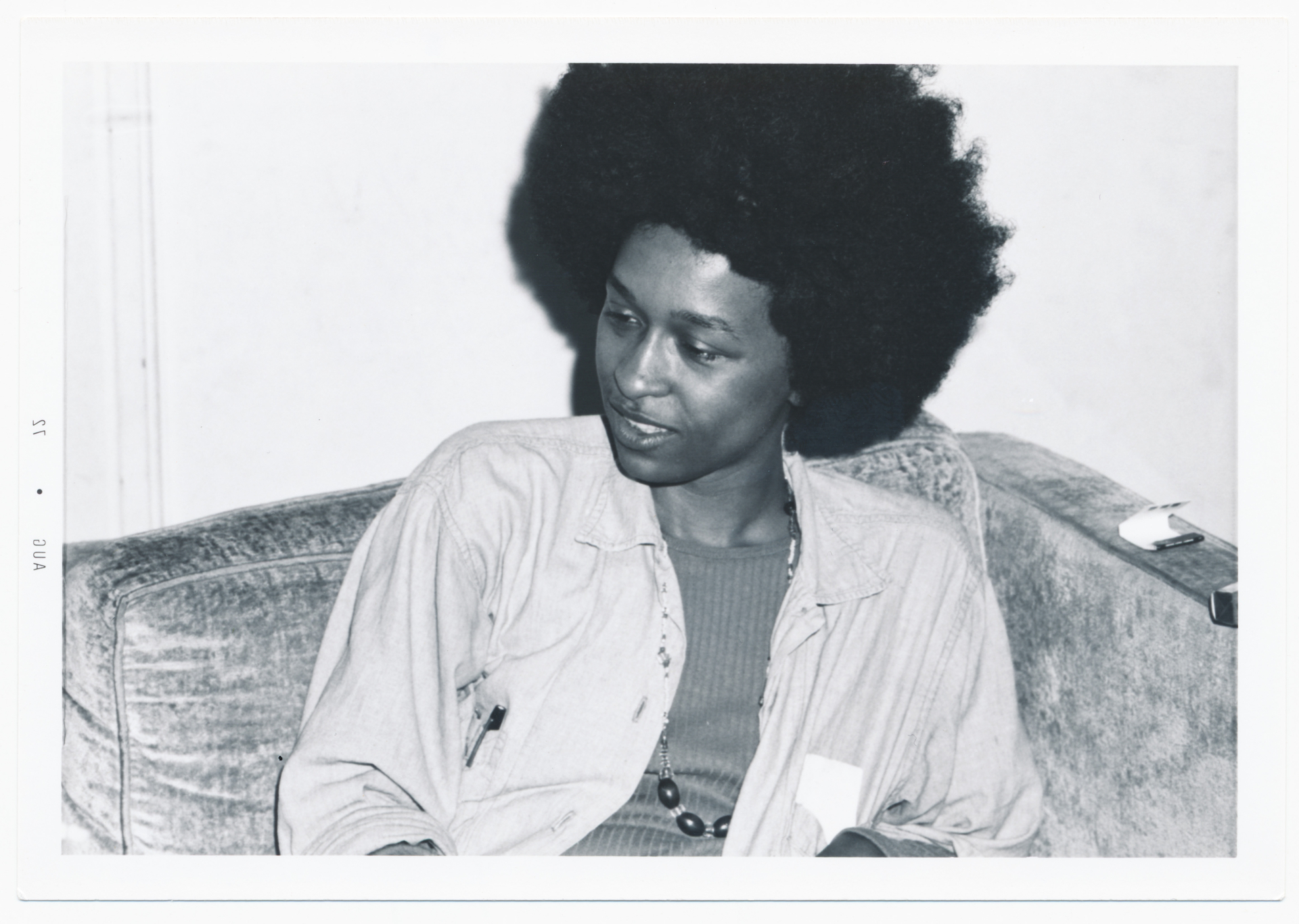Black and white image of Black woman with fro on couch