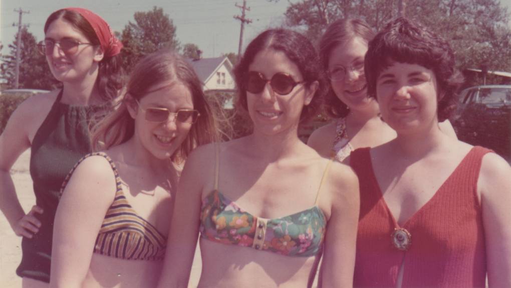 Five white women in bathing suits smile