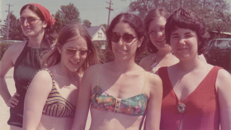 Five white women in bathing suits smile