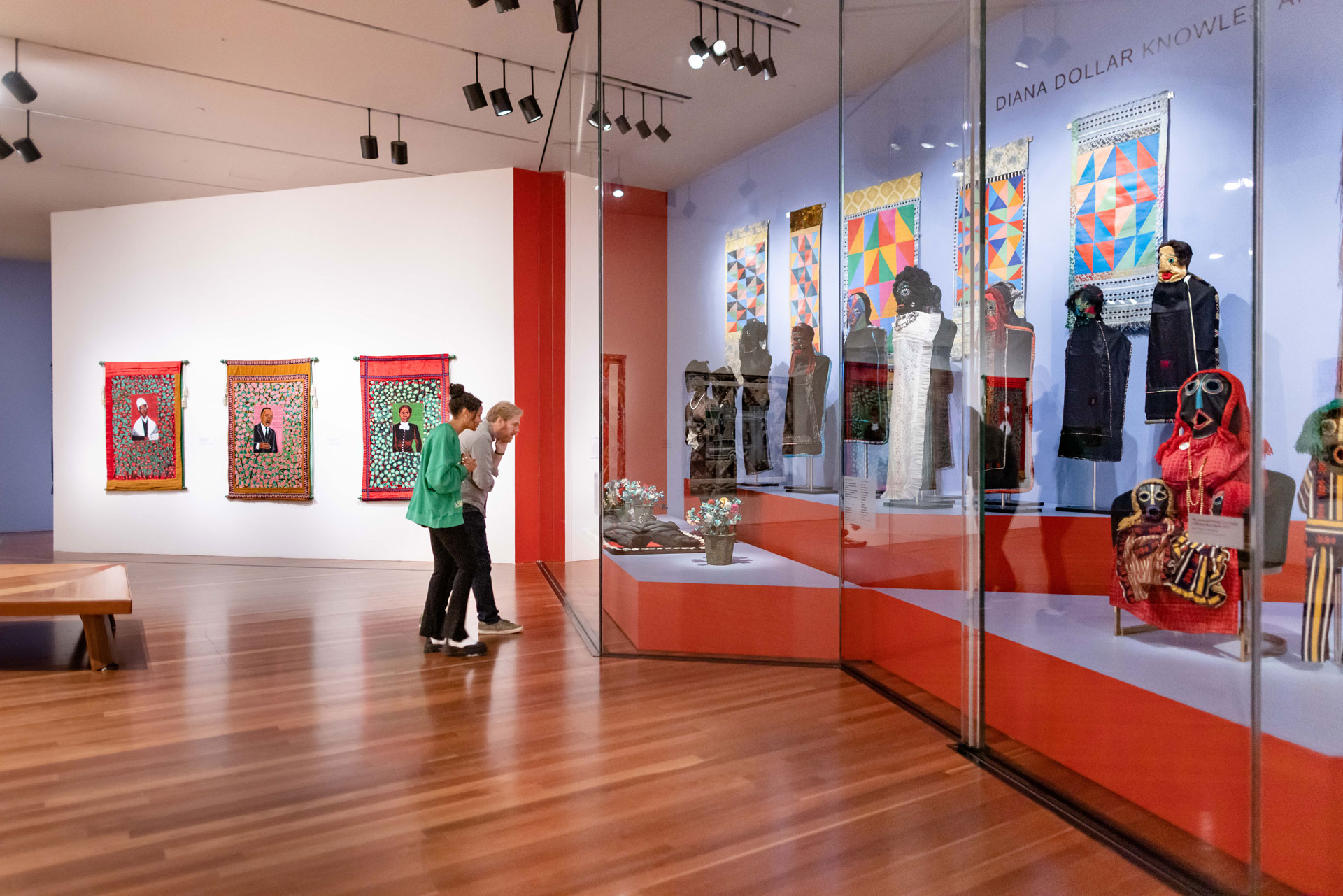 Gallery view with glass-enclosed space of life-sized sewn figures.