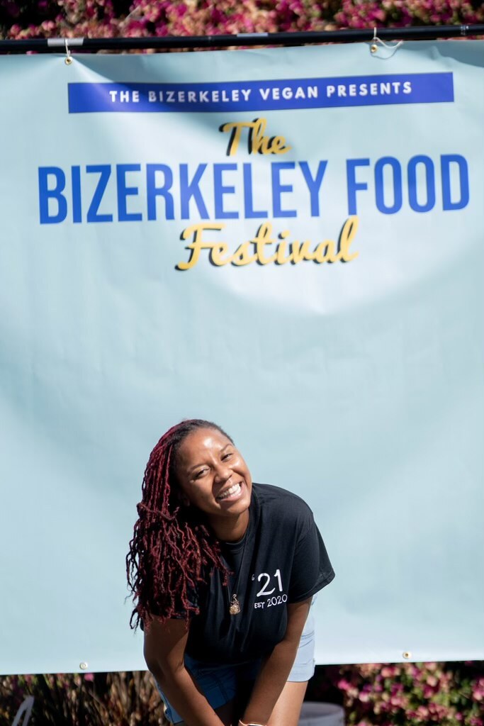 Erika Hazel, who is the founder of the Bizerkeley Food Festival, stands in front of her festival's banner while smiling