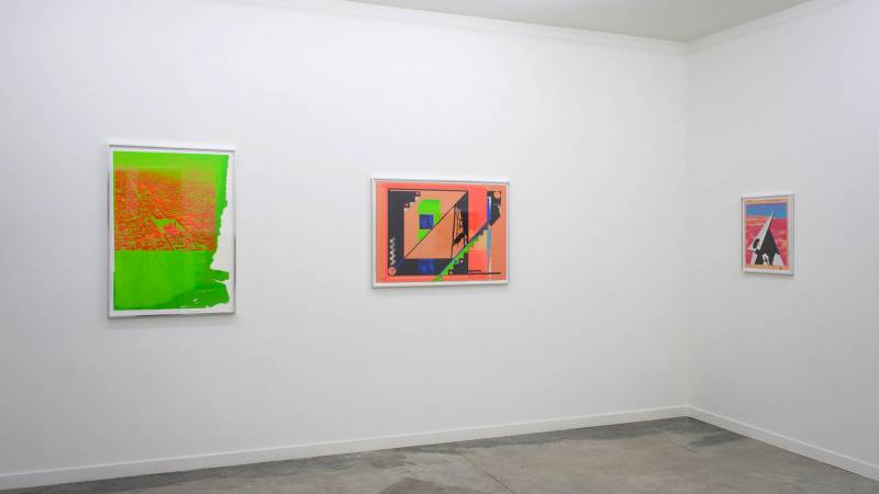 Three framed brightly colored collage works in white gallery space