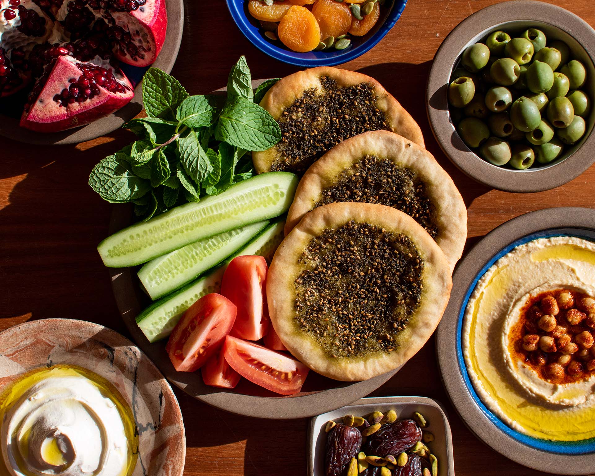 A spread of bread, olives, raw vegetable, and dips.