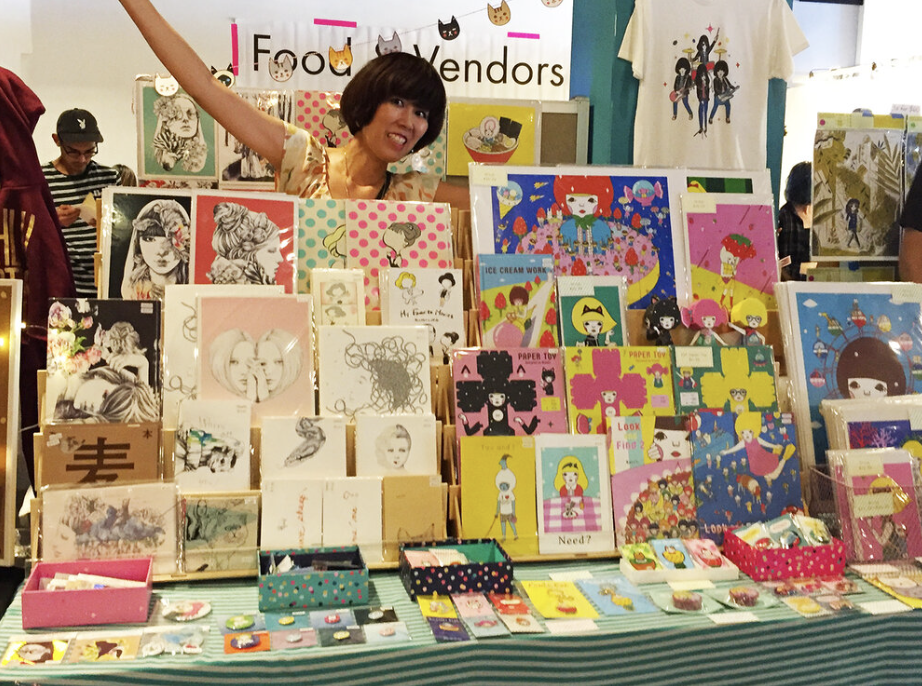 Woman smiles behind colorful display of books and zines