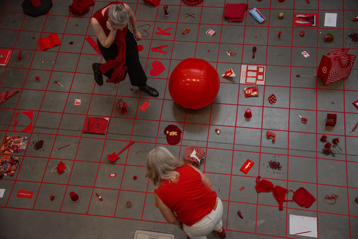 Overhead view of grid of red objects with two figures looking down