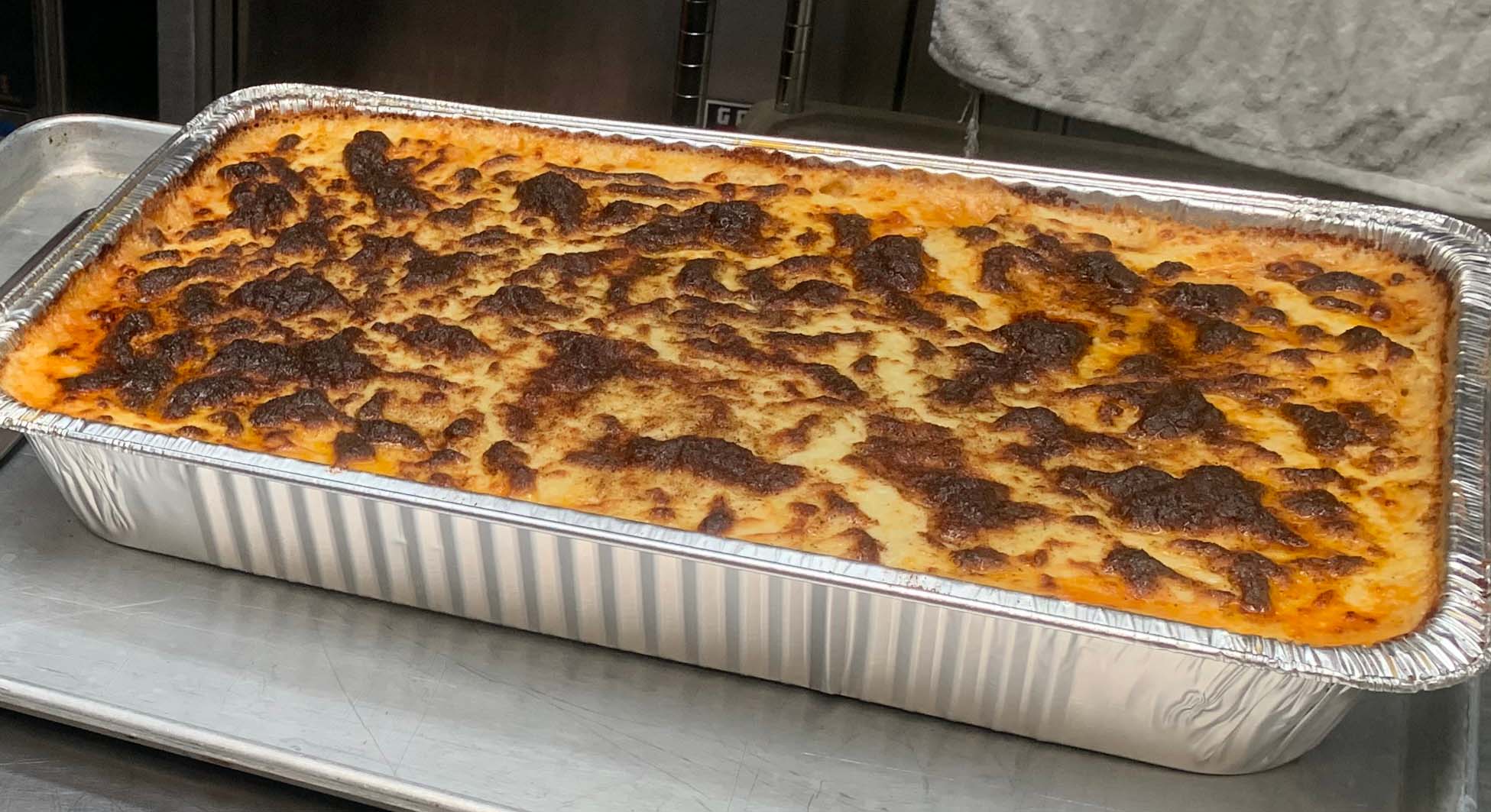 A big aluminum tray of Greek pastitsio, the top cooked to golden brown.