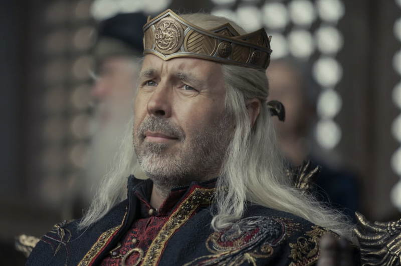 A middle aged man with long white hair wearing robes and a crown.